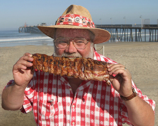 Chef Rick Browne is pictured biting into baby back ribs.