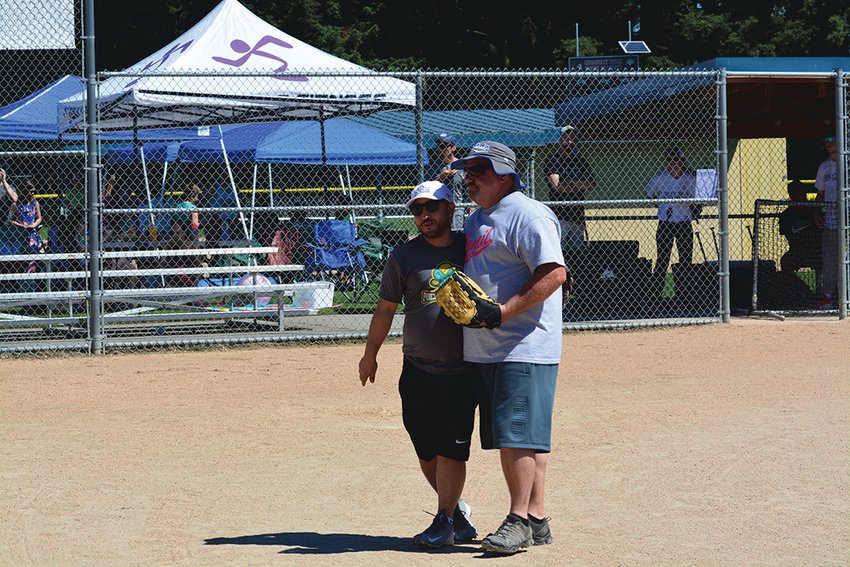 Yelm&rsquo;s Mayor Joe DePinto embraces former Yelm Chief of Police Todd Stancil, who threw out the celebratory first pitch during the second annual mushball tournament on June 26.