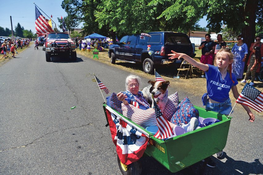 With her passengers tucked safely away in a cocoon of pillows, a girl heaves a handful of candy to waiting spectators during Roy&rsquo;s Fourth of July parade in this file photo.