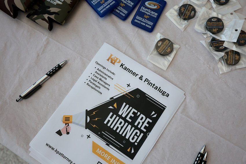 A &quot;We're Hiring&quot; pamphlet is seen on the Kanner &amp; Pintaluga table setup at the Mega Job Fair held at the FLA Live Arena on June 23, 2022, in Sunrise, Florida. The job fair had 8,000 jobs available from 100 different employers and expected approximately 3000 people to attend the fair. (Joe Raedle/Getty Images/TNS)