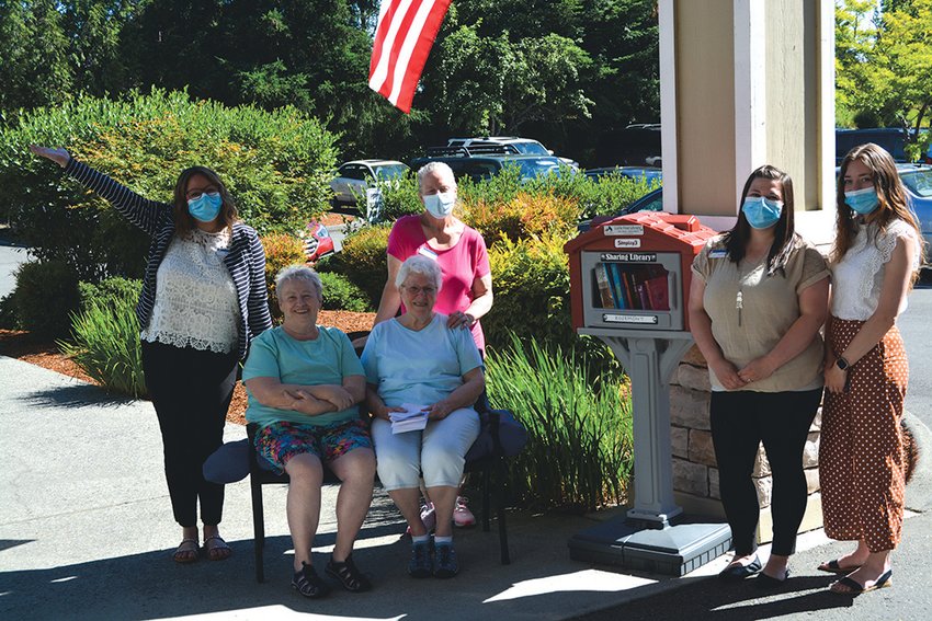 Representatives of the Prestige Senior Living Rosemont facility pose for a photo after a ribbon-cutting ceremony for a new outdoor library on Tuesday, July 12.
