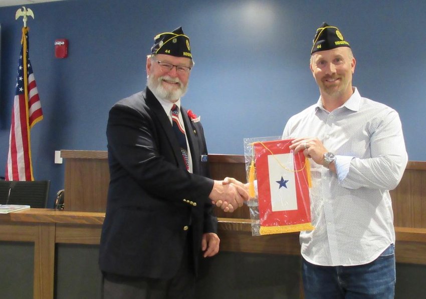 John Rose, the father of Jacinda Rose, receives a banner from Commander Darren Wertz at the American Legion Post 44 Blue Star flag ceremony on July 5.
