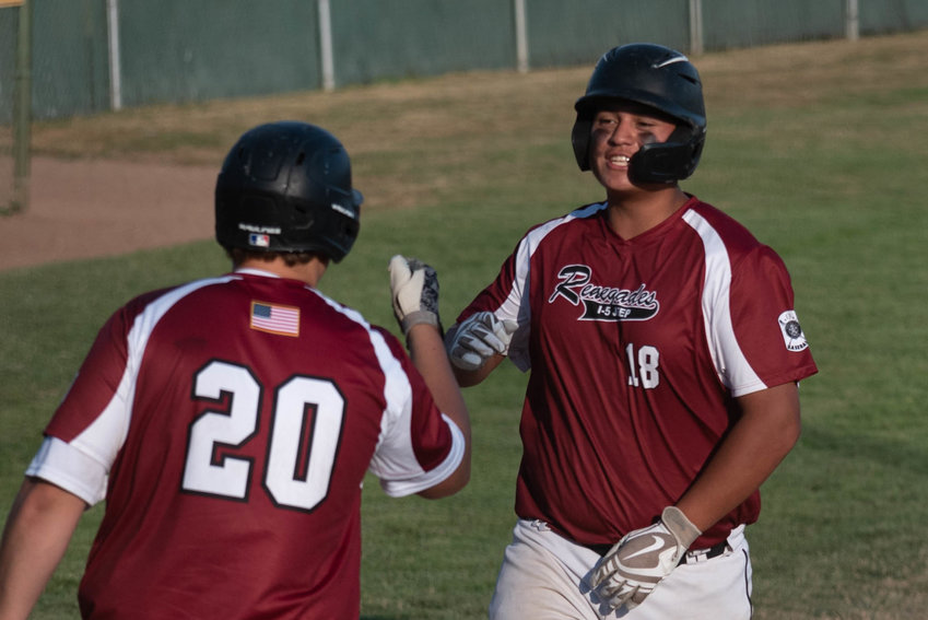 Carlos Vallejo (right) fist-bumps Jack Nelson (left) after scoring a run for the I-5 Jeep Renegades in the second round of the winner's bracket of the Junior A American Legion state tournament in Chehalis.