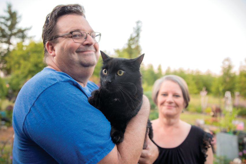 Ken and Julie Wiseman smile for a photo with their cat Raven on Wednesday after he was rescued from a utility pole by Lewis County Public Utility District employees outside their residence along Frogner Road.