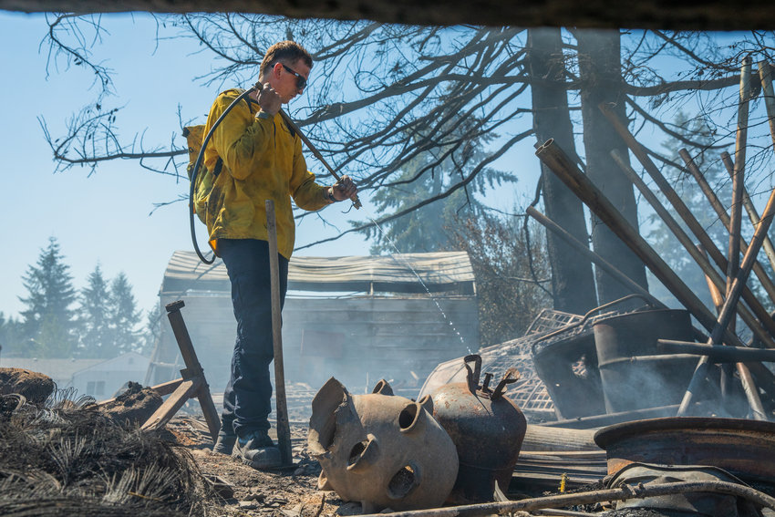West Thurston Firefighter Chris White works to extinguish hot spots along 195th Avenue Southwest in Rochester on Sunday.