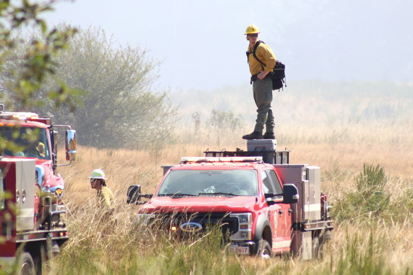A firefighter surveys the area from atop a vehicle while battling a wildfire in Rochester on Thursday.