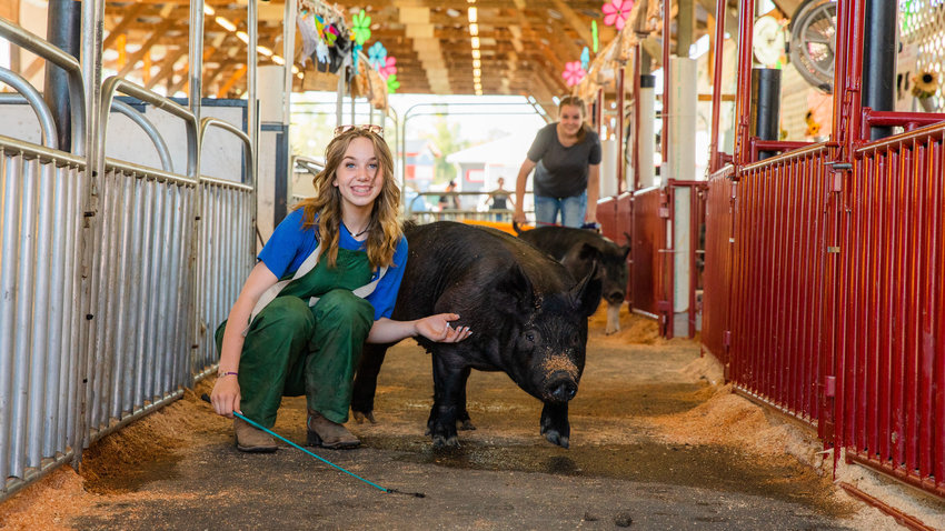 Addison Cox, 15, of Onalaska, smiles for a photo while walking pigs alongside Alex Nederlander, 16, Monday afternoon at the Southwest Washington Fairgrounds in Centralia.