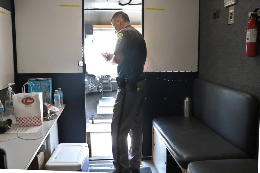 A deputy with the Lewis County Sheriff&rsquo;s Office takes a break from the afternoon heat inside the mobile command unit parked at the Southwest Washington Fairgrounds on Wednesday.