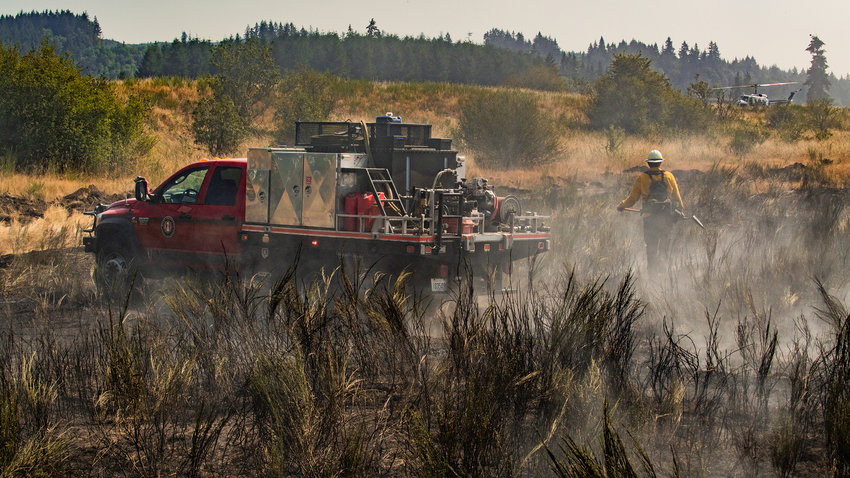 A West Thurston Fire truck drives through scorched grass and tansy while responding to a brush fire in Grand Mound on Thursday, August 11, 2022.