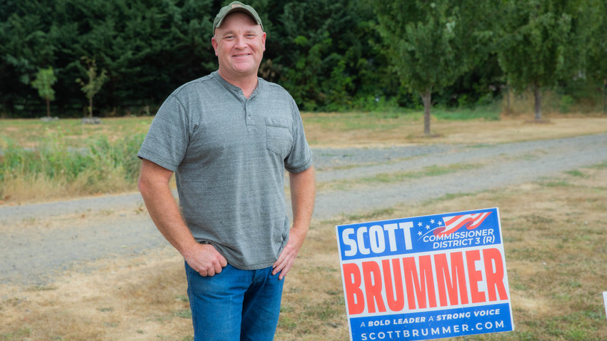 Scott Brummer smiles while standing next to his campaign sign Tuesday afternoon in Winlock.