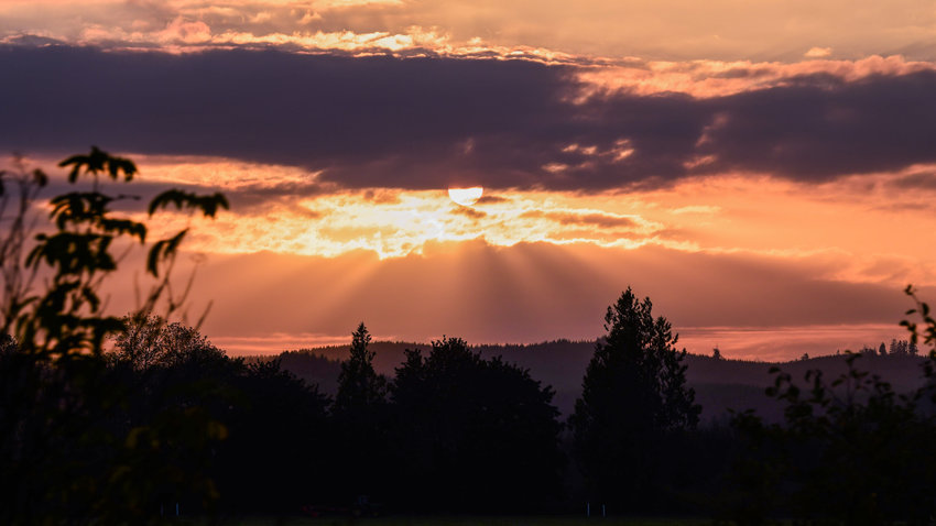 Rays of light shine through clouds over the Willapa Hills Monday evening as the sun sets.
