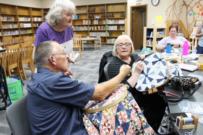 Rick Sundstrom shows an incredibly small quilting needle to Judy Cobd and Susy Carpenter during a meetup of the In Stitches quilting group, which will hold its final public show Sept. 30 and Oct. 1 at Centralia Christian School.