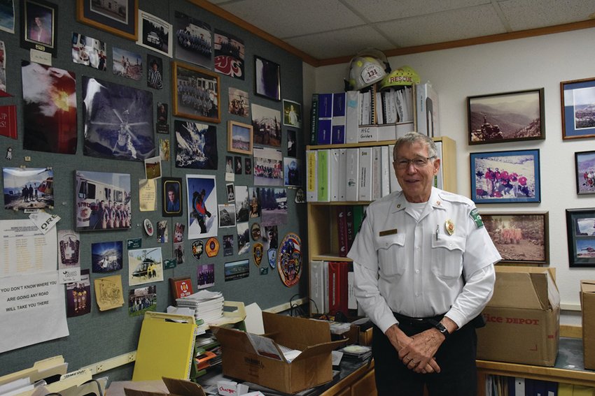 Former Clark County Fire District 13 and North Country EMS chief Tom McDowell stands in his office in 2018, in front of nearly five decades of memorabilia from his public safety career in the Yacolt area. His death was announced Oct. 5 by both agencies.