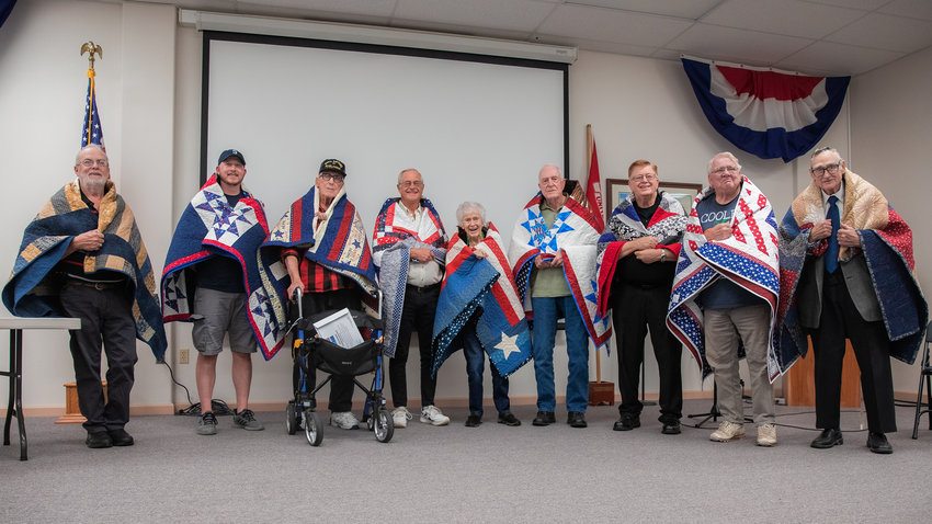 From left, Edward Nieman, Josh Luck, Robert Swift, Buddy Rose, Glenna Ralff, Ken Halphide, Terry Leno, Gerald Gifford and Daryl Rank pose for a photo during a Quilts of Valor ceremony honoring their service on Friday at the Veterans Memorial Museum in Chehalis.