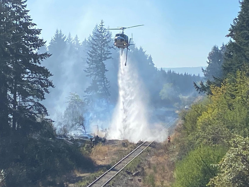 A helicopter dumps water to combat a brush fire in Yelm on Oct. 12.