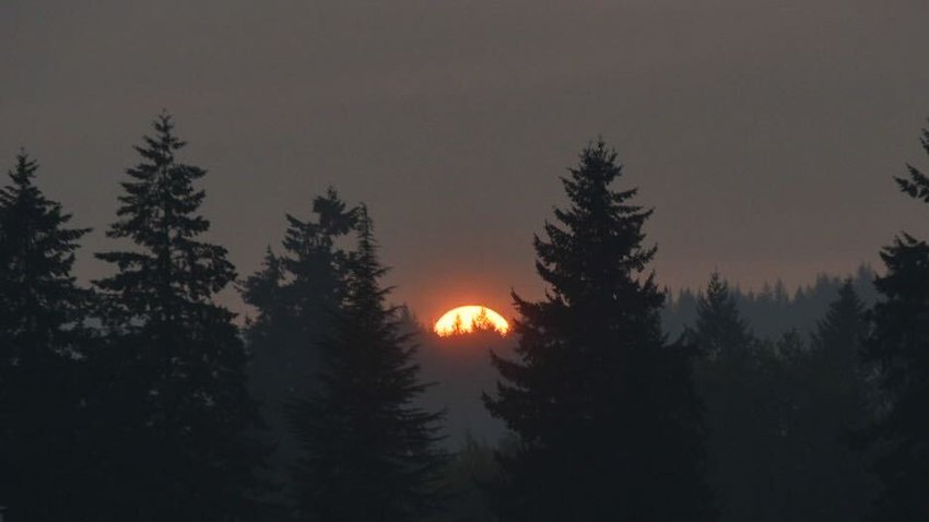 The sun glows orange through wildfire smoke as it sets behind the Chehalis-Centralia airport on Wednesday evening.