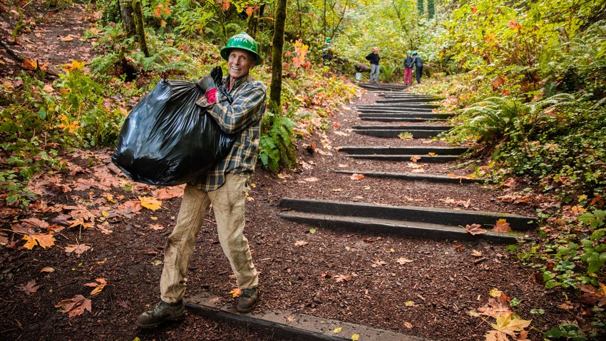 Ross Olson smiles while carrying a bag of trash down the Seminary Hill Natural Area in Centralia on Wednesday.