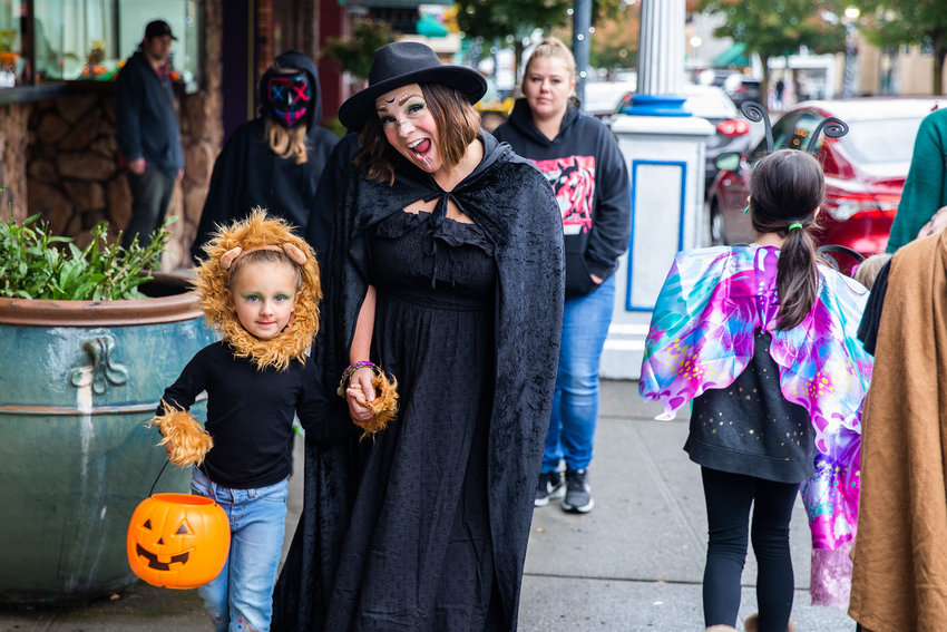 Rae Childers, 4, walks with Nellie Logan while dressed as a lion on Halloween in downtown Centralia.