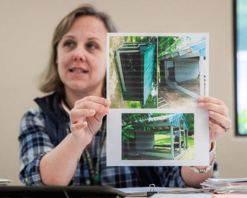 Lewis County Humane Officer Alishia Hornburg holds up photos of a structure one community member built for his registered dog.