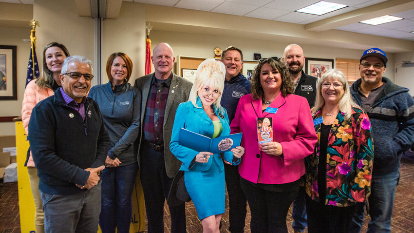 Rotarians and staff from United Way stand with a cardboard cutout of Dolly Parton to celebrate the three-year anniversary of the Dolly Parton Imagination Library being kicked off in Lewis County at the Holiday Inn in Chehalis in November 2022. The program provides books for young kids at no cost to the families.