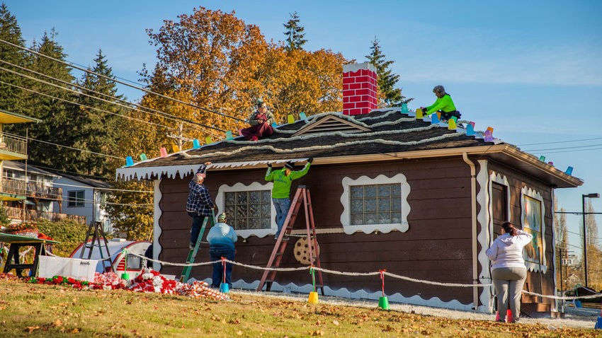 Terry Harris joins volunteers in putting up decorations for the famous gingerbread house next to the Chehalis Parks and Recreation department on Saturday.