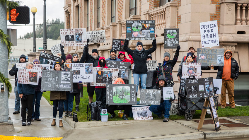 Friends of Aron Christensen pose for a photo while holding signs outside the Lewis County Courthouse while demanding justice in Chehalis on Sunday.