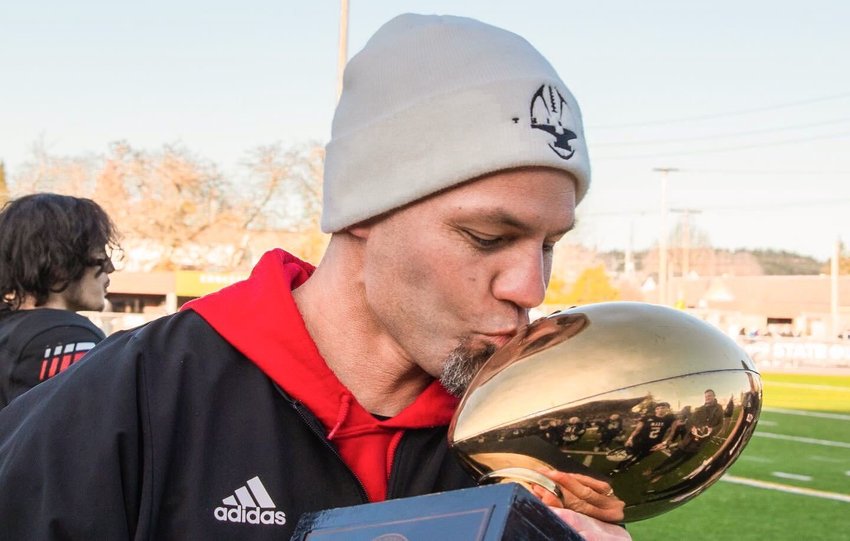 Jason Ronquillo, the head coach for Yelm, kisses the 3A State Championship trophy his team won.
