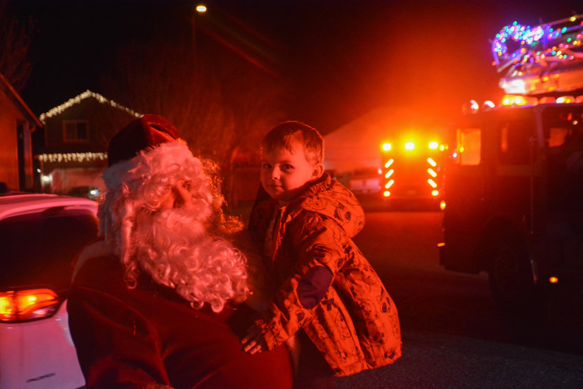 Santa poses with his first visitor of the night on Dec. 15, 2022 as Southeast Thurston Fire drove Santa around the community.