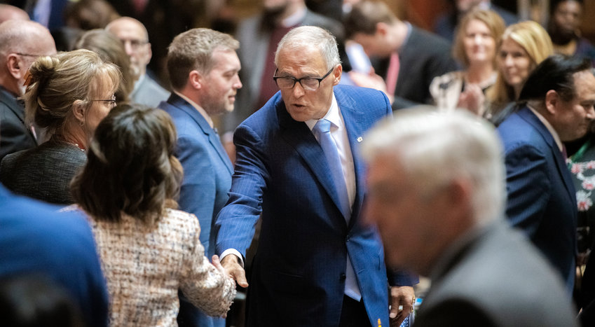 Gov. Jay Inslee shakes hands on the house floor following the 2023 State of the State speech Tuesday in Olympia.