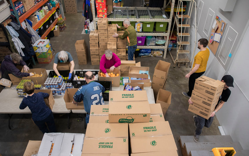 Volunteers work to package up boxes after filling them with food items at the Gather Annex in Centralia Thursday morning.