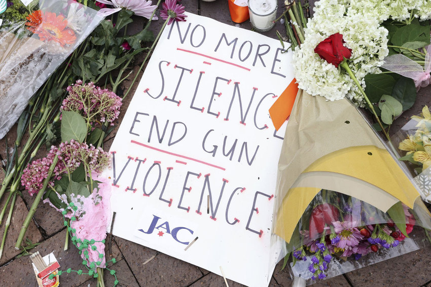 A sign saying &quot;No more silence, end gun violence&quot; sits next to flowers and candles at the corner of Central and St. Johns avenues in Highland Park, Illinois, on July 6, 2022, as a memorial honoring the victims of the Fourth of July parade mass shooting. (Antonio Perez/Chicago Tribune/TNS)