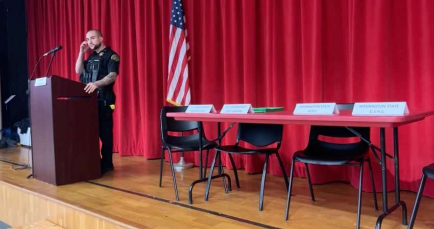 Thurston County Sheriff Derek Sanders speaks to the crowd during the Sunday meeting next to chairs reserved for Thurston County commissioners and representatives of state agencies.