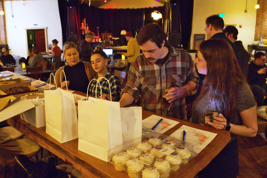 Centralia Downtown Association Block Party attendees peruse a silent baked goods auction at The Juice Box on Wednesday.
