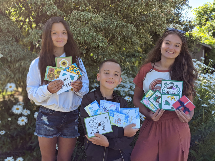 Della, Harrison and Ada Austin pose with cards made for Ukraine soldiers.