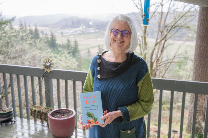 Gretchen Staebler smiles for a photo with her book titled &ldquo;Mother Lode, Confessions of a Reluctant Caregiver&rdquo; at her residence off Seminary Hill Road in Centralia last February.