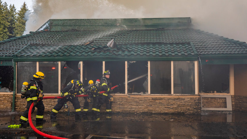 A Riverside firefighter works with Chehalis Fire crews to put out flames inside the former location of Papa Pete&rsquo;s and Shari&rsquo;s Cafe in Centralia in February.