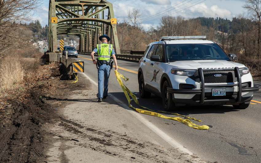 A member of the Washington State Patrol carries caution tape away from a scene west of Chehalis on Tuesday.