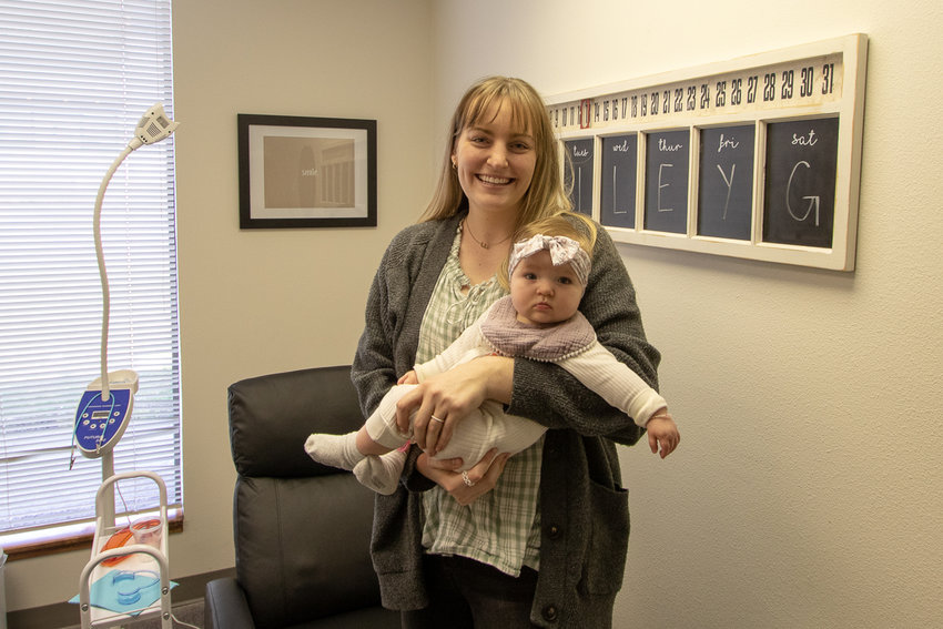 SmileyG Teeth Whitening Clinic owner Andie Williams stands in her clinic on South Market Boulevard with her eight-month-old daughter, Gwendolyn.