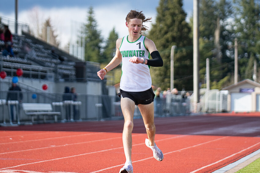 Tumwater's John Hoffer checks his watch as he crosses the finish line to win the boys 1,600 meters at a 2A EvCo meet on April 19 at Tumwater District Stadium.