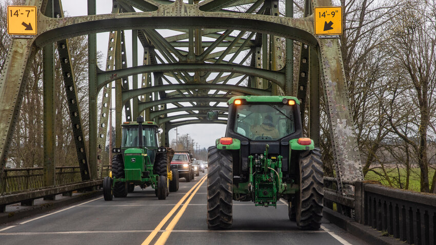 Tractor drivers gesture toward one another while traveling in opposite directions over the Chehalis River bridge along state Route 6 on the morning of Thursday, April 20, 2023.