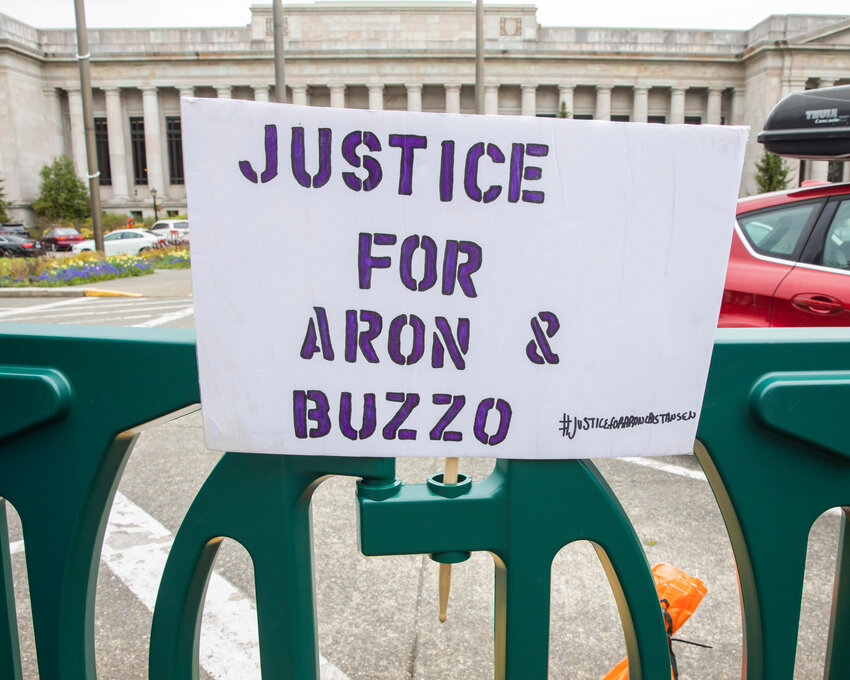 Visitors from across the Pacific Northwest display signs in protest while demanding answers in the deaths of Aron Christensen and his dog Buzzo outside the Washington State Capitol Building in Olympia on Sunday, April 23, 2023.
