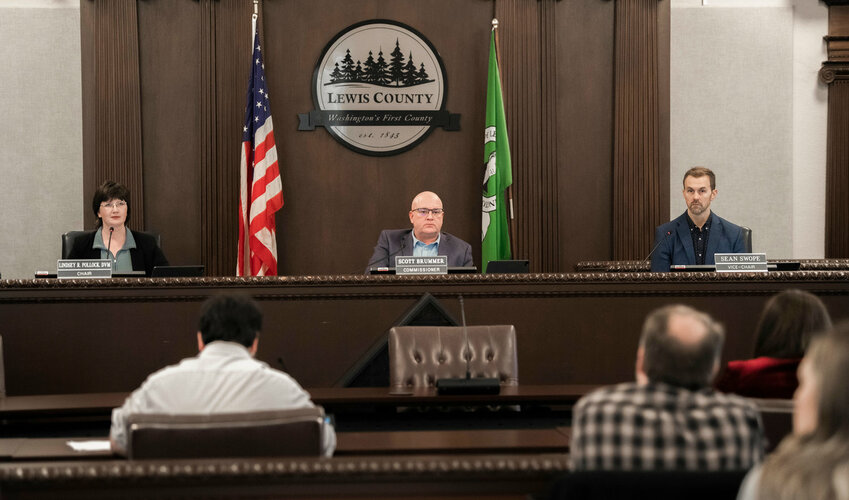 FILE PHOTO &mdash; Lewis County Commissioners Lindsey Pollock, Scott Brummer and Sean Swope prepare to pass resolutions during a  meeting in Chehalis.