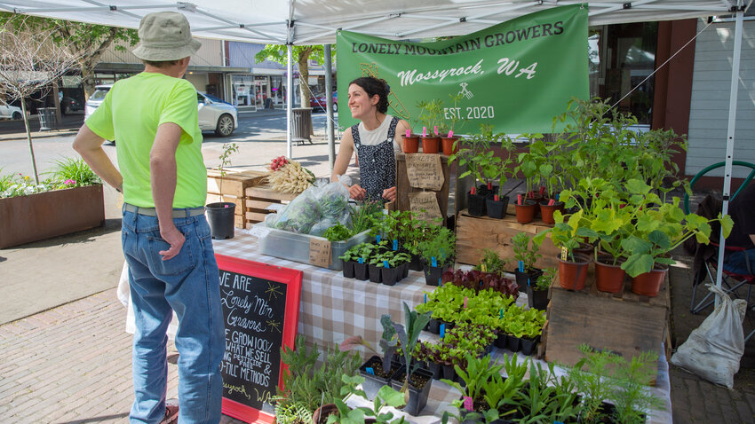 Aubrey Kendall, of Lonely Mountain Growers in Mossyrock, smiles while talking to visitors at the Centralia Farmers Market in the Pine Street Plaza on Friday, May 12.