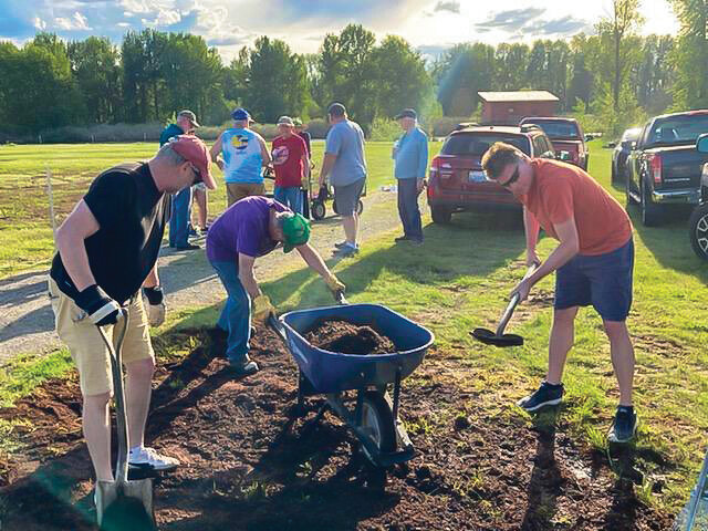 Members of the Ridgefield Lions Club apply soil to level out a field designated for the organization&rsquo;s Sausage Festival.