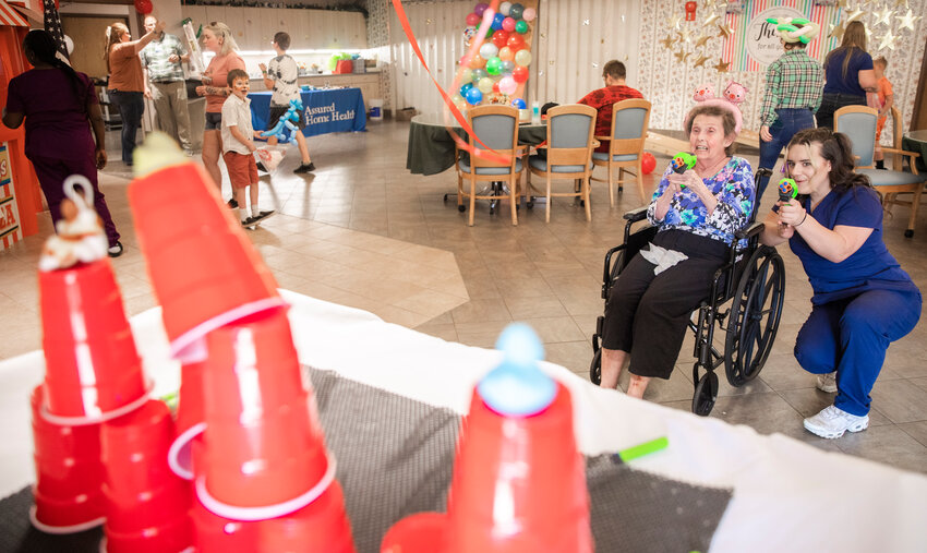 Sandra VanSant aims to knock down cups alongside Tonika Radach, far right, at the Sharon Care Center during a senior fair in Centralia on Friday, May 19.