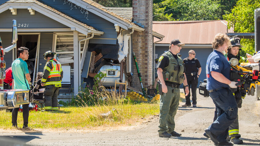 Medical personnel, crews from Riverside Fire Authority, Centralia Police and Lewis County Sheriff deputies respond to the scene of a crash where a car went through the walls of a residence Monday afternoon in Centralia along North Pearl Street.