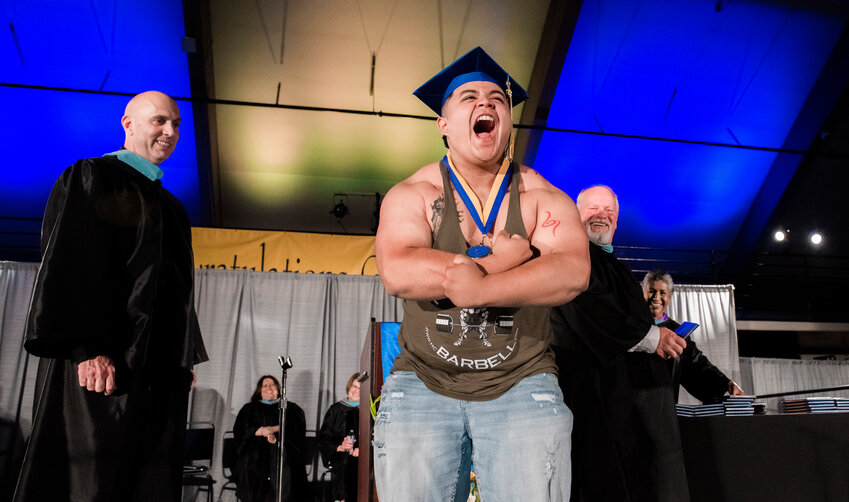 Rochester graduate Adan Baires cheers and flexes after receiving his diploma and taking off his gown on stage at St. Martin&rsquo;s University in Lacey on Sunday, June 11.