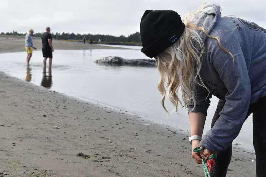 Ocean Shores resident Maddie Pittman ties off a line to secure a dead gray whale to the shore so it doesn&rsquo;t drift off before being necropsied after attempting to aid it on June 27.