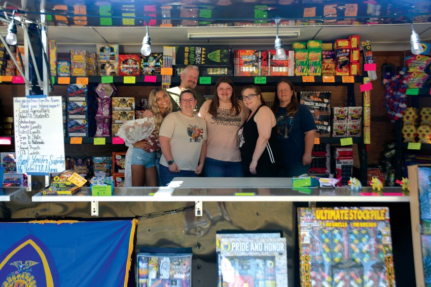 Members of the Yelm FFA Alumni Association smile inside the firework booth.