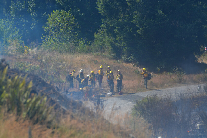 A group of firefighters discuss a game plan while they stand in thick smoke on July 6 near Roy.